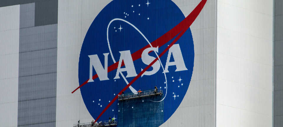Workers painting the NASA meatball on the side of the Vehicle Assembly Building