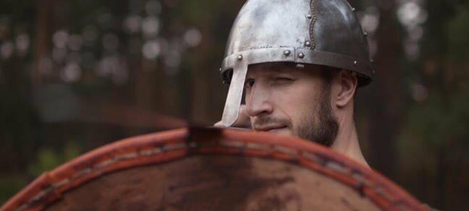 Man in helmet looks uncertain, holds up shield. Photo by Shutterstock