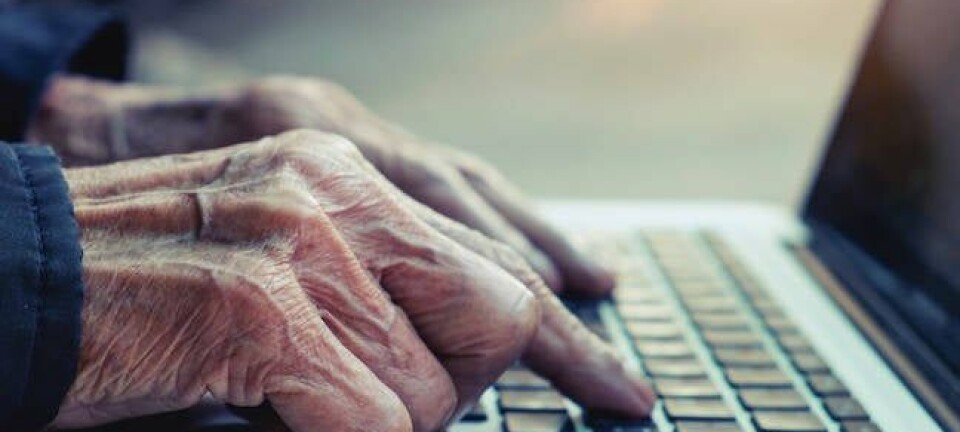 Old man's hands typing on laptop