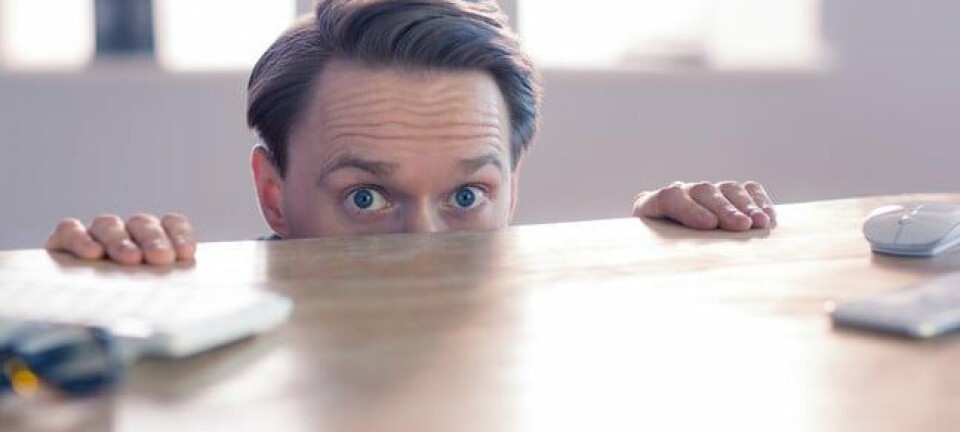 Scared looking office consultant hides under desk