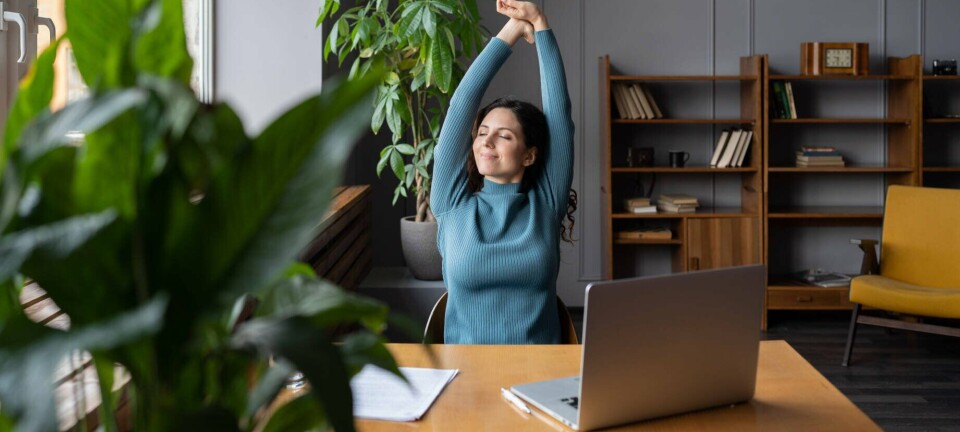 A happy looking worker at their desk stretching