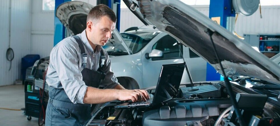 A mechanic tuning a car engine using a laptop