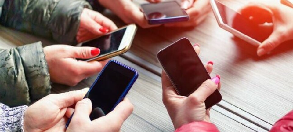 A group of people hold out mobile phones in a circle. Photo by Shutterstock