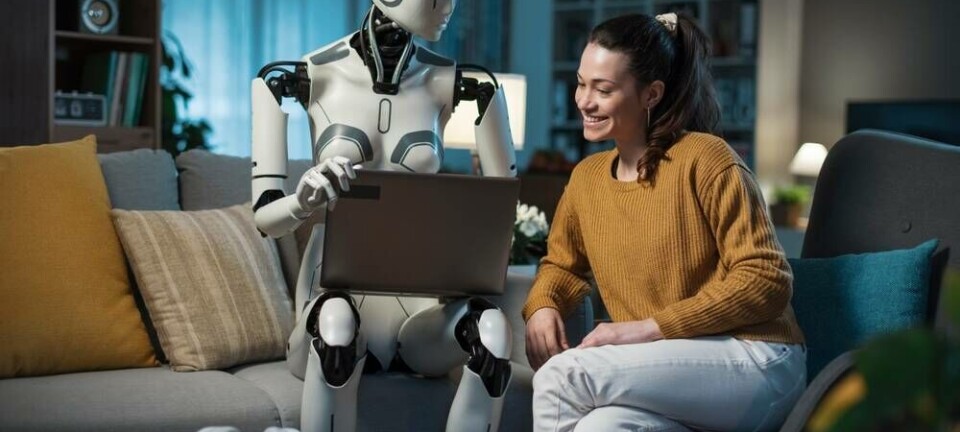 A friendly robot working with someone on a laptop at home