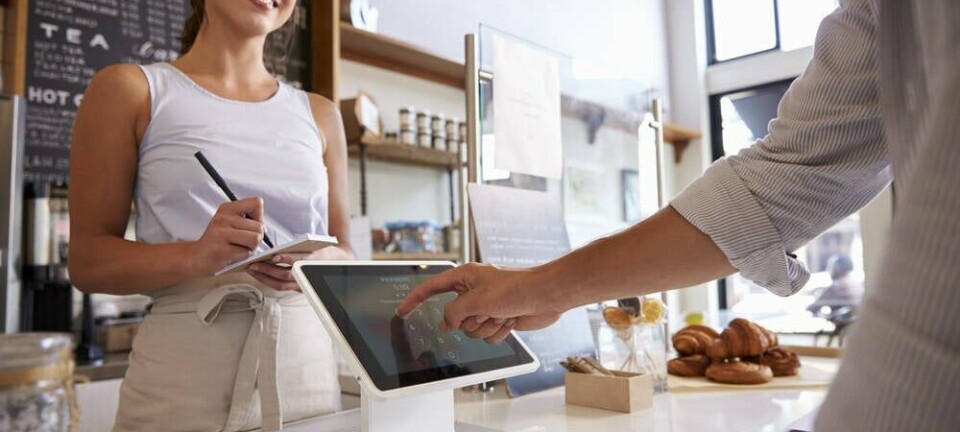 Someone paying for a coffee in a cafe using a Square terminal