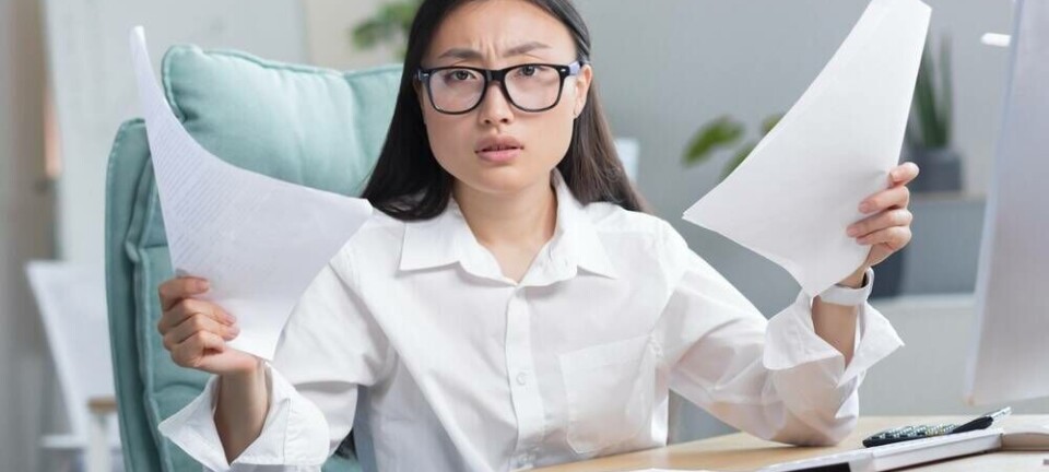 Someone in an office looking irritated by invoices and bills