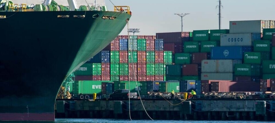 Dockworkers tying up container ship to dock with stacked containers in the background at the Port of Los Angele