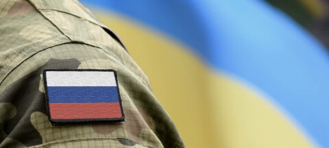 Flag of Russia on military uniform and flag of the Ukraine at background.
