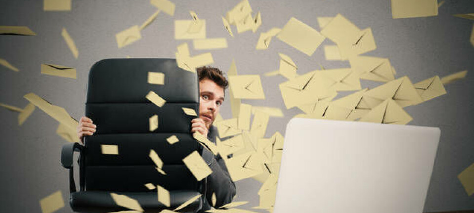 A man hiding from a lot of emails coming from a laptop