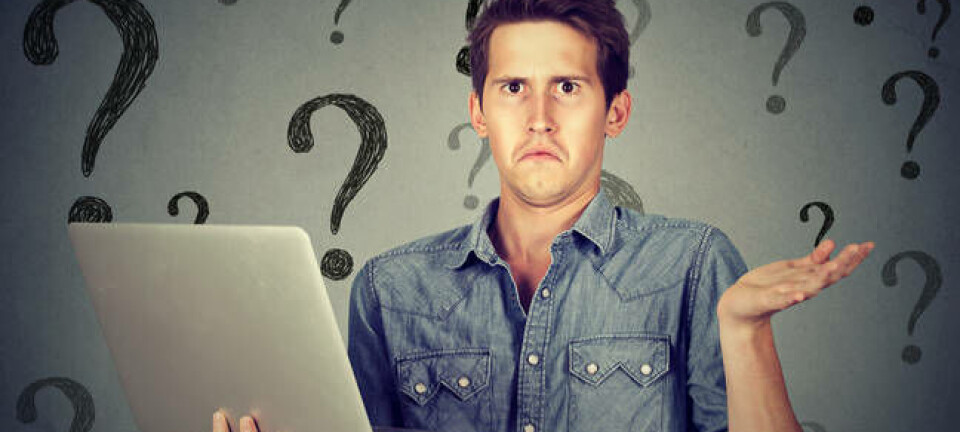 A man shrugs at a laptop with a background of question marks