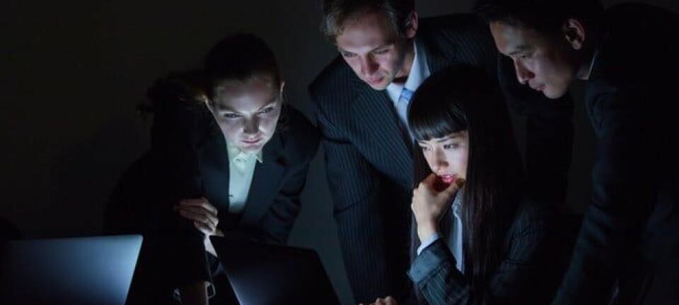 group of people in suits look at laptop screens