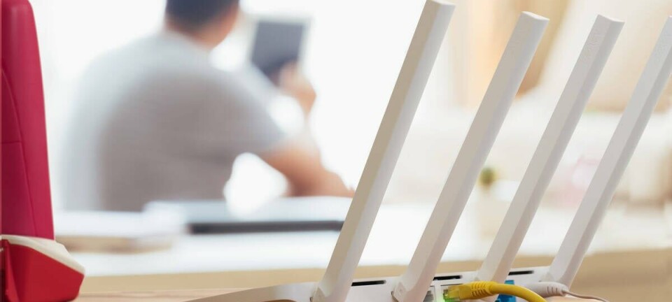 closeup of a wireless router and a man using smartphone on living room at home office