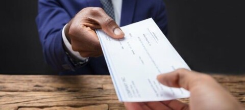 Man handing another person a paycheck