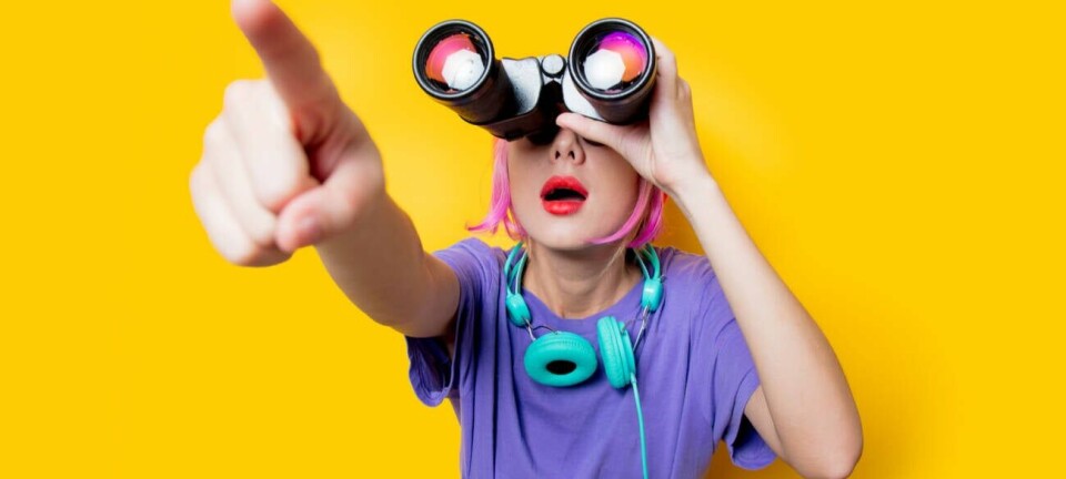 Someone holding binoculars to their eyes and pointing out something in the distance