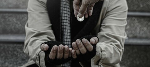 Dropping a coin into poor homeless beggar's hands