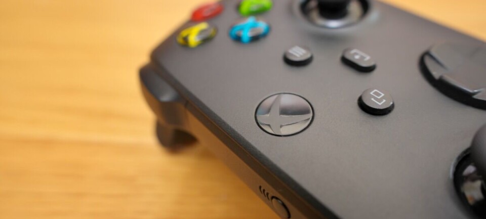 Close-up of a black Xbox controller on a wooden surface.