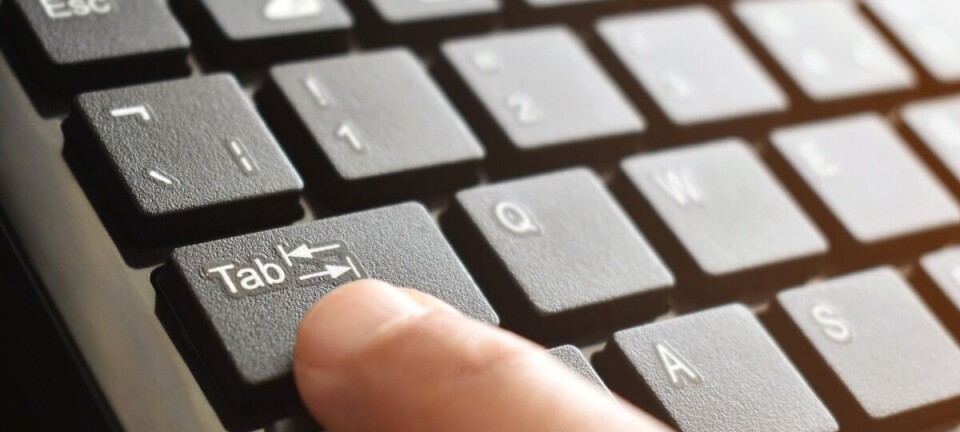 Close-up of a finger pressing the Tab key on a black computer keyboard.