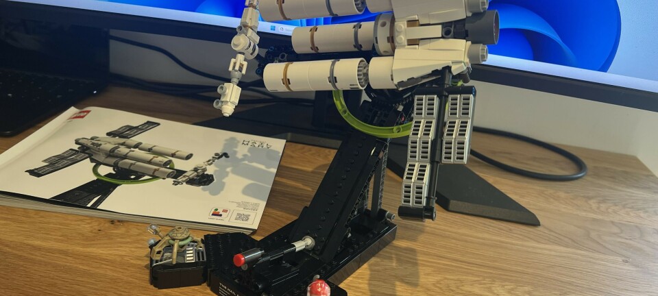 A Lego Technic spacecraft model displayed on a desk beside an instruction booklet and a small minifigure.