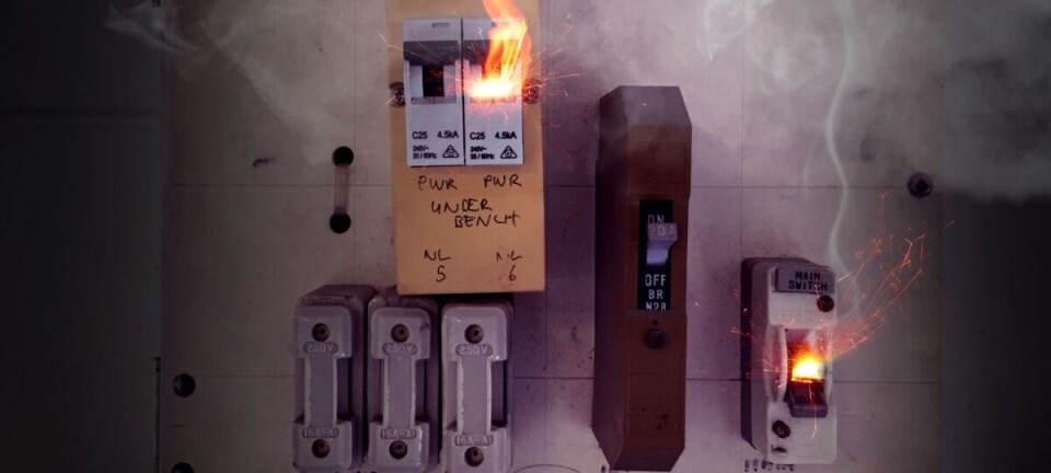 Electrical breaker panel with a small fire and smoke coming from the top left breaker.