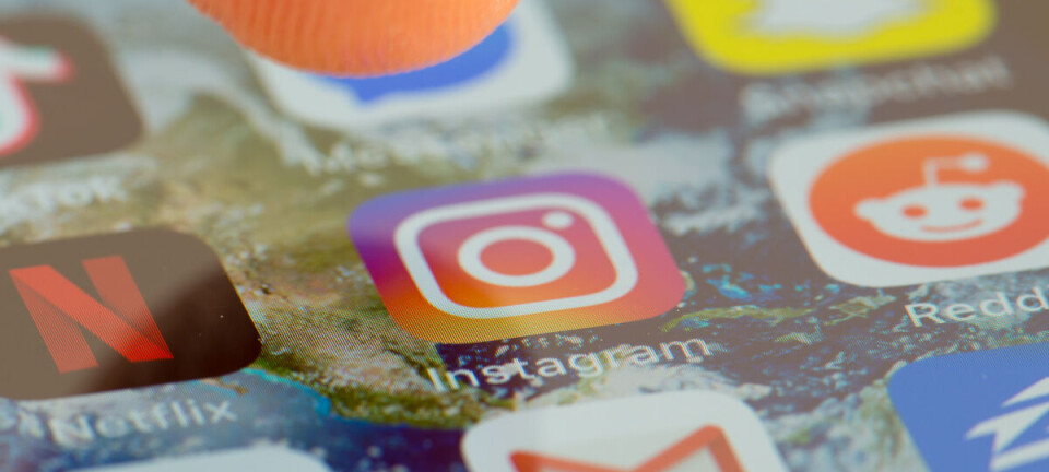 Close-up of a finger touching a smartphone screen with social media app icons.